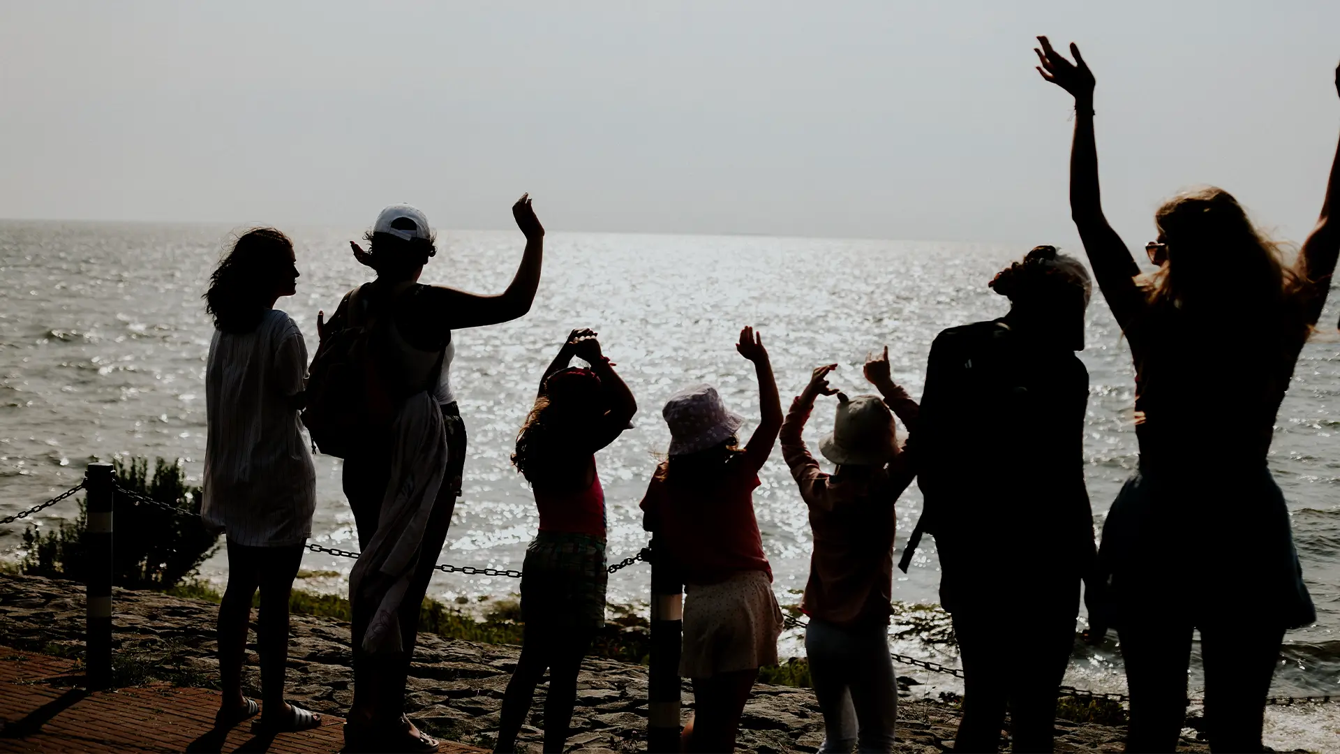 Eine Gruppe von kleineren und größeren Kindern posieren vor dem Meer für ein Foto