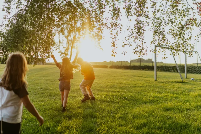 Kinder spielen auf einer Wiese bei Sonnenuntergang