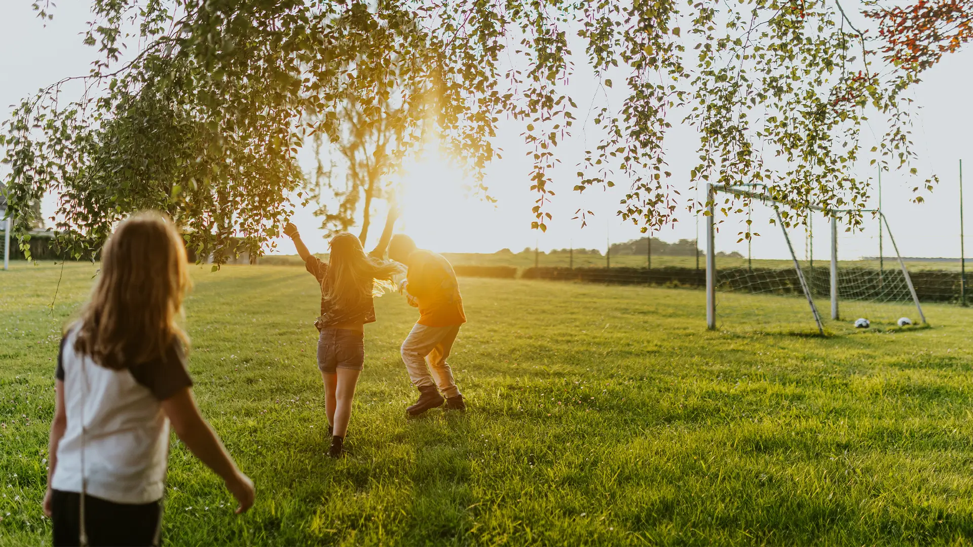 Kinder spielen auf einer Wiese bei Sonnenuntergang